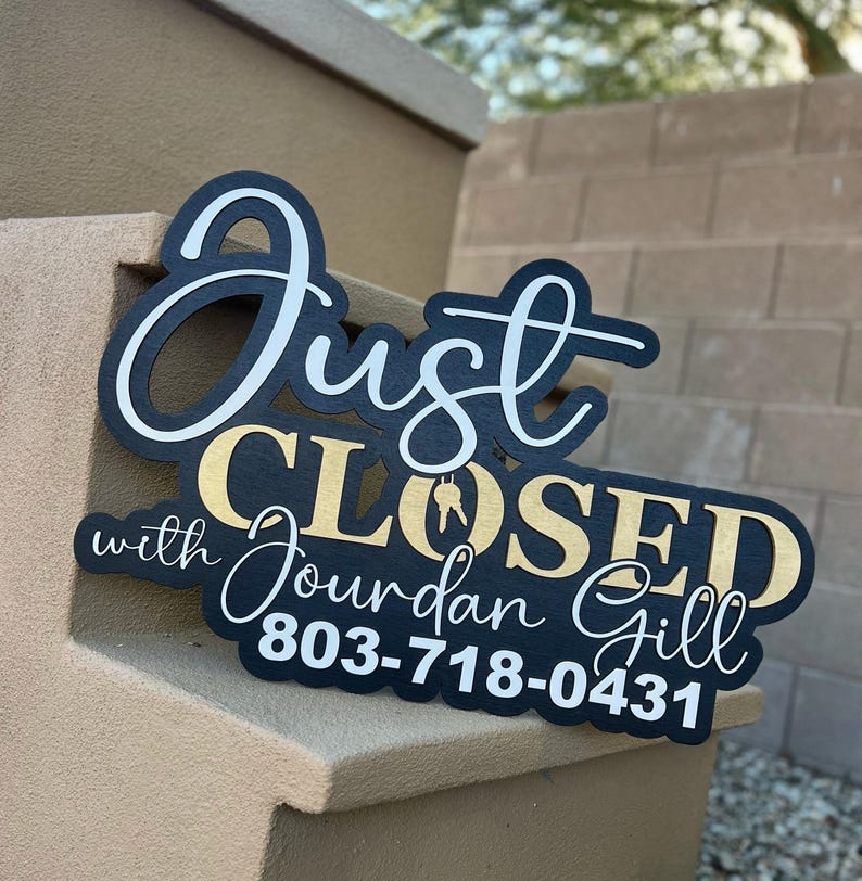 Pu&ograve; includere: Un cartello nero con scritte bianche e dorate che recita Just CLOSED with Jourdan Gill 803-718-0431. La parola Just &egrave; in carattere corsivo bianco, CLOSED in lettere dorate con un'icona a forma di chiave e il resto &egrave; in bianco.