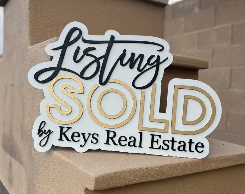 May include: White sign with black and gold lettering that reads "Listing SOLD by Keys Real Estate".