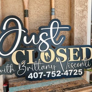 Pu&ograve; includere: Un cartello nero e oro con scritte bianche che recita Just CLOSED with Brittany Visconti 407-752-4725. La parola Just &egrave; in corsivo bianco, CLOSED in lettere dorate con un'icona a forma di chiave e il resto del testo &egrave; in bianco.