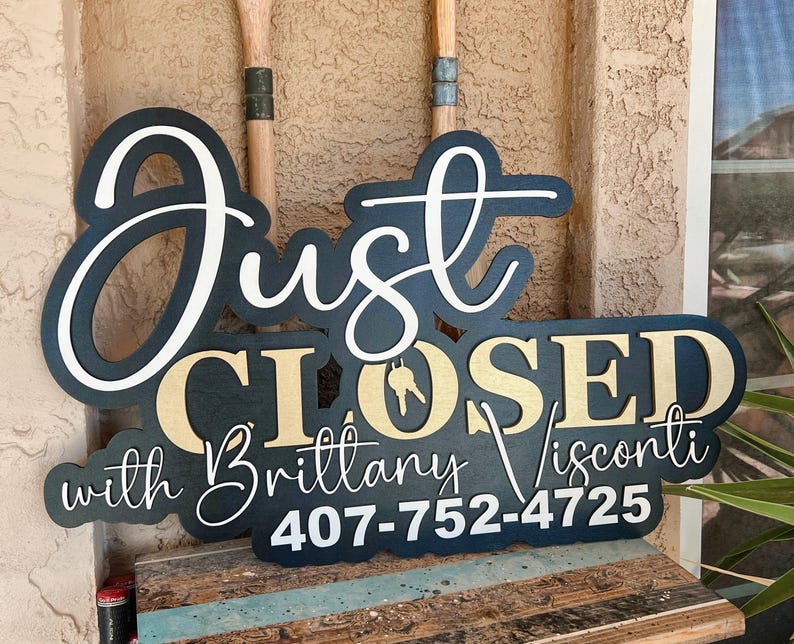 Pu&ograve; includere: Un cartello nero e oro con scritte bianche che recita Just CLOSED with Brittany Visconti 407-752-4725. La parola Just &egrave; in corsivo bianco, CLOSED in lettere dorate con un'icona a forma di chiave e il resto del testo &egrave; in bianco.
