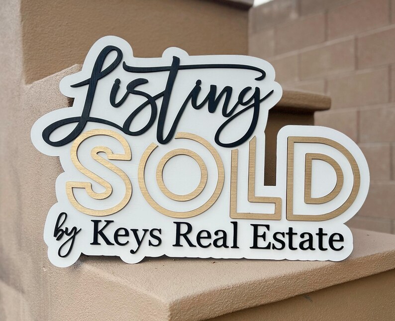 May include: White sign with black and gold lettering that reads "Listing SOLD by Keys Real Estate".