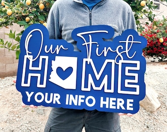 May include: Blue wooden sign with white lettering that reads "Our First Home" with an outline of the state of Arizona and a heart in the center. The sign also has the text "Your Info Here" at the bottom.