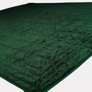 Puede incluir: Una alfombra de oraci&oacute;n verde oscuro con una superficie texturizada y acolchada. La alfombra tiene un patr&oacute;n sutil y un borde verde oscuro.