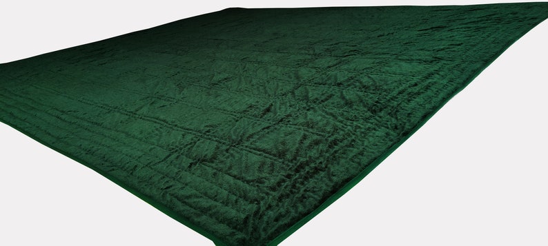 Puede incluir: Una alfombra de oraci&oacute;n verde oscuro con una superficie texturizada y acolchada. La alfombra tiene un patr&oacute;n sutil y un borde verde oscuro.