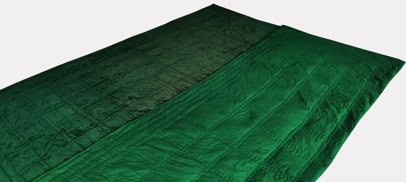 Puede incluir: Una manta acolchada verde doblada por la mitad. La manta tiene un sutil efecto degradado, pasando de un verde m&aacute;s oscuro a un verde m&aacute;s claro.