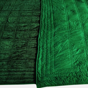 Puede incluir: Una colcha de terciopelo verde con un patr&oacute;n acolchado en ambos lados. Un lado tiene un patr&oacute;n de cuadr&iacute;cula simple, mientras que el otro lado tiene un dise&ntilde;o m&aacute;s intrincado.