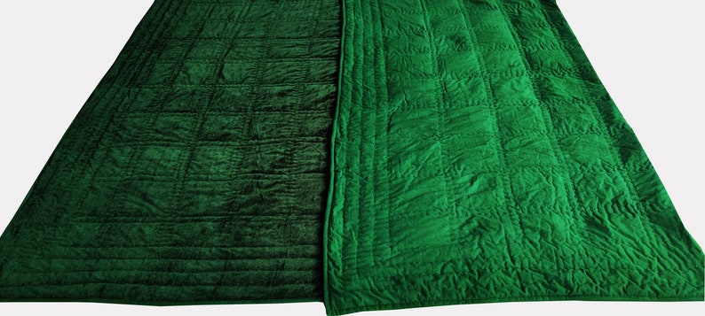 Puede incluir: Una colcha de terciopelo verde con un patr&oacute;n acolchado en ambos lados. Un lado tiene un patr&oacute;n de cuadr&iacute;cula simple, mientras que el otro lado tiene un dise&ntilde;o m&aacute;s intrincado.