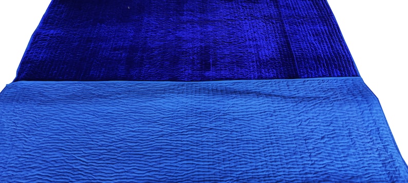 K&ouml;nnte beinhalten: Eine blaue Samtdecke mit einem gesteppten Muster auf der Unterseite.