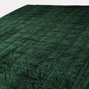 Puede incluir: Una manta acolchada de color verde oscuro con un patr&oacute;n de diamantes.