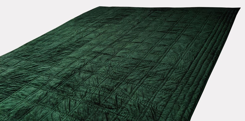 Puede incluir: Una manta acolchada de color verde oscuro con un patr&oacute;n de diamantes.