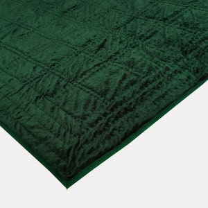 Puede incluir: Una manta de felpa verde oscuro acolchada con una superficie texturizada.