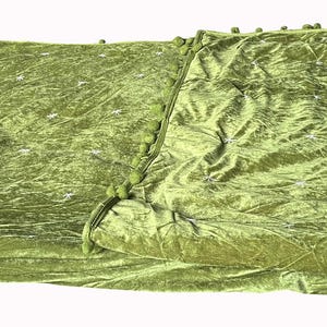 May include: A green velvet tablecloth with a subtle shimmer. The fabric is folded in half and has a slightly textured surface.