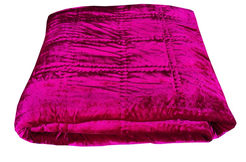 K&ouml;nnte beinhalten: Eine gefaltete rosa Samtdecke mit gestepptem Muster.