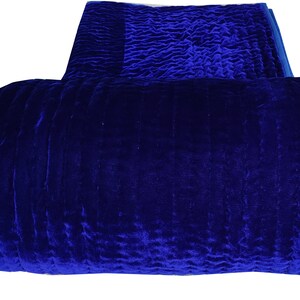 K&ouml;nnte beinhalten: Eine tiefblaue Samtdecke, die zu einem Zylinder gefaltet ist. Die Decke hat eine strukturierte Oberfl&auml;che und ist aus einem weichen, luxuri&ouml;sen Stoff gefertigt.