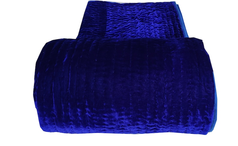 K&ouml;nnte beinhalten: Eine tiefblaue Samtdecke, die zu einem Zylinder gefaltet ist. Die Decke hat eine strukturierte Oberfl&auml;che und ist aus einem weichen, luxuri&ouml;sen Stoff gefertigt.