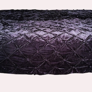 May include: A black velvet quilted throw blanket with a subtle ombre effect. The blanket has a diamond pattern and is accented with tassels on the corners.