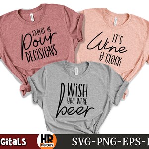 Puede incluir: Tres camisetas con diferentes lemas. La primera camiseta es de color rosa polvoriento con el texto "Expert in Pour Decisions". La segunda camiseta es de color melocot&oacute;n claro con el texto "It's Wine O'Clock". La tercera camiseta es de color gris claro con el texto "Wish You Were Beer".