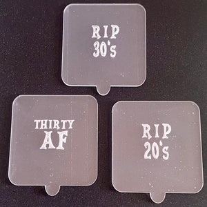 May include: Three clear plastic square-shaped signs with white text. The signs read "RIP 30's", "RIP 20's", and "THIRTY AF".
