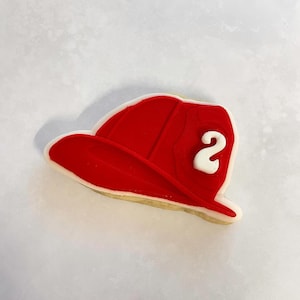 May include: A red and white sugar cookie decorated to look like a firefighter's hat with the number "2" on the side.