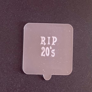 May include: White plastic stencil with the text "RIP 20's" in a decorative font.