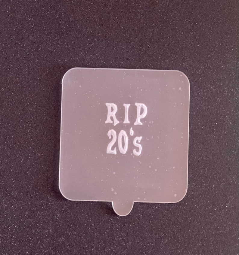 May include: White plastic stencil with the text "RIP 20's" in a decorative font.
