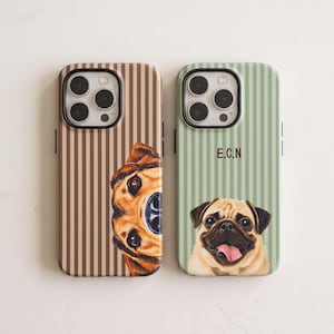 Pode incluir: Duas capas de telemóvel com riscas verticais. A capa esquerda é castanha com uma ilustração parcial da cara de um cão. A capa direita é verde sálvia com uma ilustração de um pug e as letras E.C.N em texto castanho escuro.
