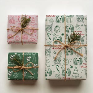 May include: Three rectangular gift boxes wrapped in patterned paper. One small pink box, one small green box, and one large white box. All feature line drawings of dogs, cats, and holiday icons with the text merry christmas and twine bows.