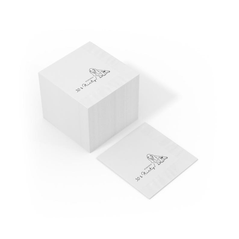 May include: A stack of white square napkins with a black and white illustration of a rabbit and the text "30 & Flirty" printed on them. One napkin is separate from the stack.