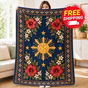 May include: A navy blue blanket featuring a gold sunburst design, red hibiscus flowers, white flowers, and gold stars. The blanket has a decorative border with a geometric pattern. A red circle with the words "FREE SHIPPING" is in the upper right corner.