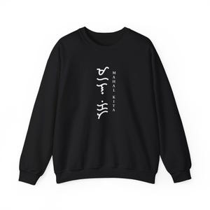 May include: A black long-sleeve sweatshirt featuring white text printed vertically in the centre. The design includes the words "MAHAL KITA" in a standard font next to a column of white Baybayin script characters.