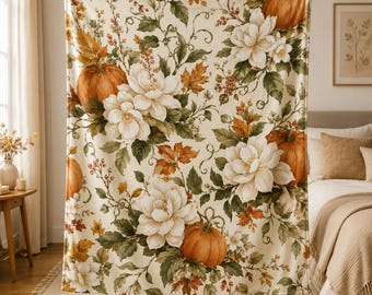 May include: A cream-colored throw blanket featuring a repeating pattern of orange pumpkins, large white flowers, green leaves, and brown autumn foliage. The design covers the entire surface of the rectangular fabric, showcasing a botanical theme.