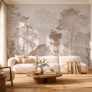 May include: A large-scale wall mural featuring a sepia-toned forest landscape with layered trees and foliage. The mural serves as a backdrop for a white modular sofa, a round wooden coffee table, and a matching armchair on a woven rug.