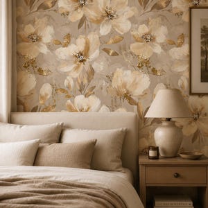 May include: Wallpaper featuring a large-scale floral pattern in shades of beige, cream, and metallic gold. The design includes painterly flower blossoms and foliage set against a neutral background, creating a repeating botanical motif.