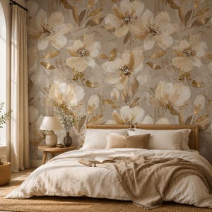 May include: A bedroom featuring wallpaper with a large-scale floral pattern in shades of cream, beige, and metallic gold. The bed has a light-coloured duvet, a textured throw blanket, and several pillows. A wooden nightstand holds a lamp and vase.