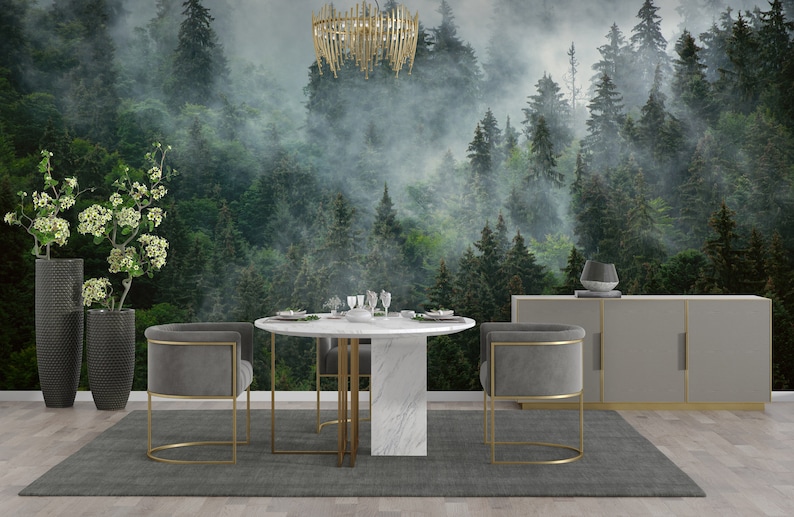 May include: A dining room with a gray rug, a round marble table with gold legs, and two gray velvet chairs with gold frames. The wall behind the table features a mural of a misty forest with tall green trees.