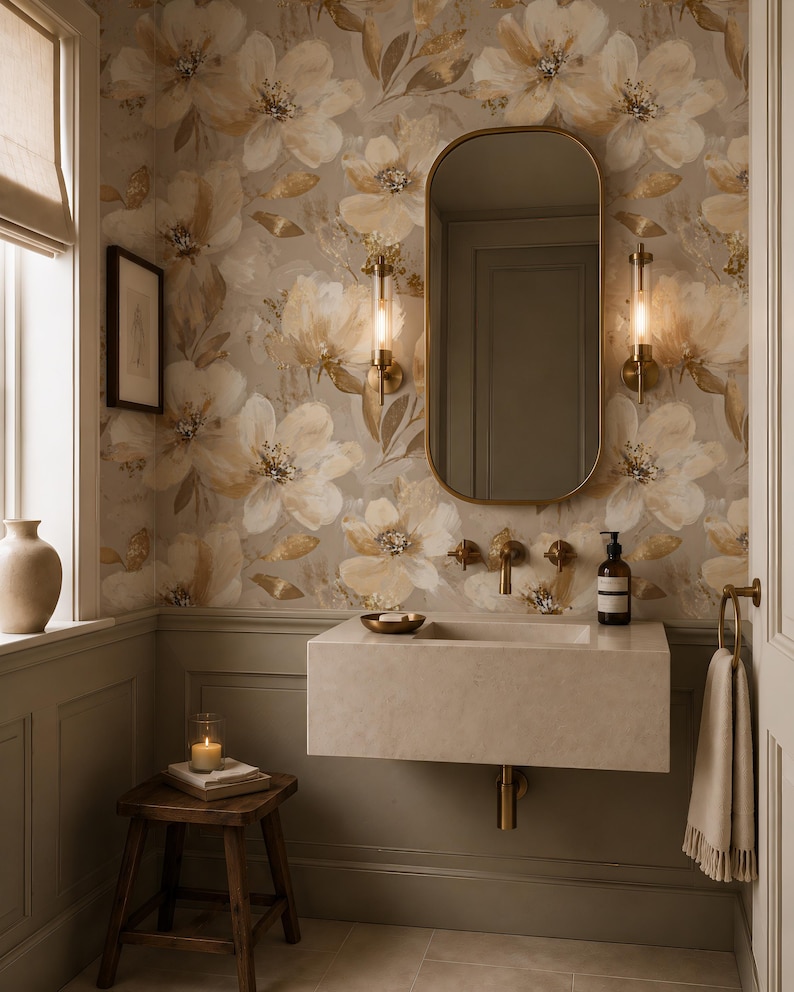 May include: A bathroom interior featuring floral wallpaper in beige and gold tones, a rectangular stone wall-mounted sink, a brass faucet, and an oval mirror. Two cylindrical wall sconces flank the mirror, with a wooden stool and towel nearby.