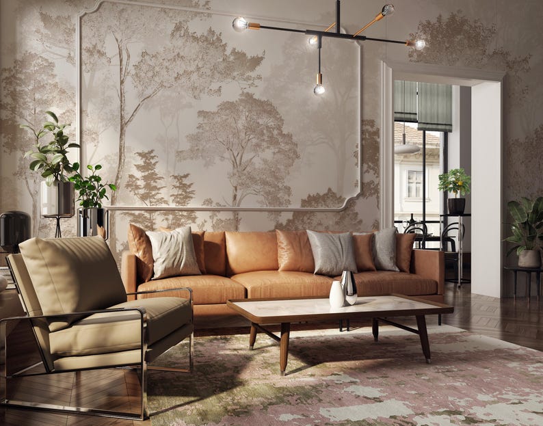 May include: A tan leather sofa with light grey throw pillows, a tan armchair with a chrome frame, and a rectangular coffee table with a white marble top. The room features a large wall mural of trees and a modern black metal chandelier with bulbs.