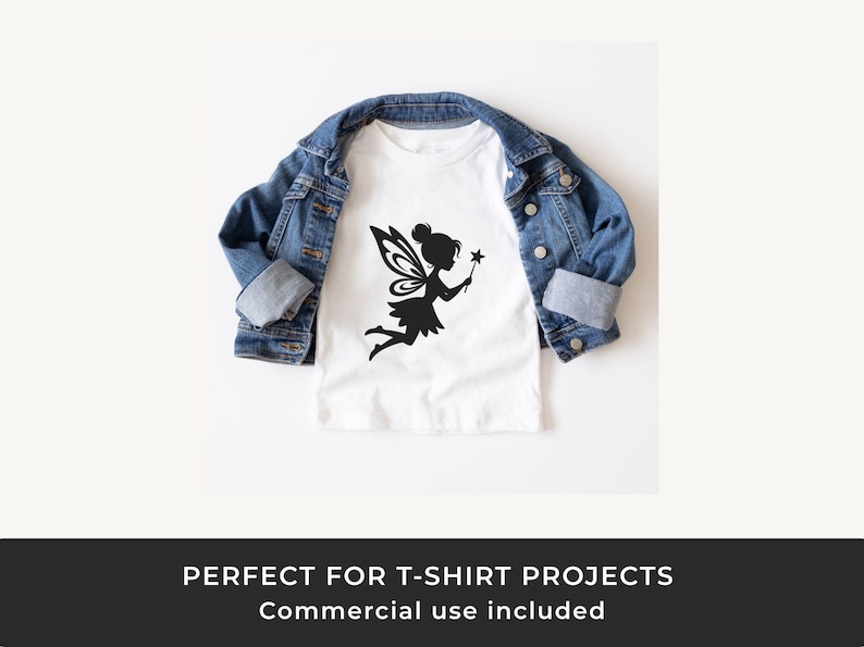 Op de afbeelding: Wit T-shirt met een zwart silhouet van een fee die een toverstaf vasthoudt, met een spijkerjasje eroverheen. Het fee&euml;nontwerp heeft gedetailleerde vleugels en een speelse pose. Het shirt wordt gepresenteerd tegen een witte achtergrond.
