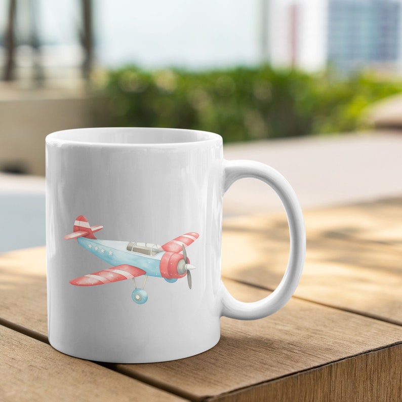 May include: White ceramic mug with a red, white, and blue airplane illustration. The airplane has a red and white striped tail and wings.