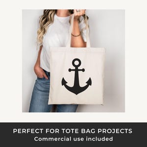 May include: Cream-colored tote bag with a large black anchor design. The bag is held by a person wearing a white t-shirt and blue jeans. The tote bag has a simple, nautical theme.