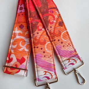 May include: Three colorful fabric straps with a pink, orange, and white floral pattern. Each strap has a silver metal clasp.