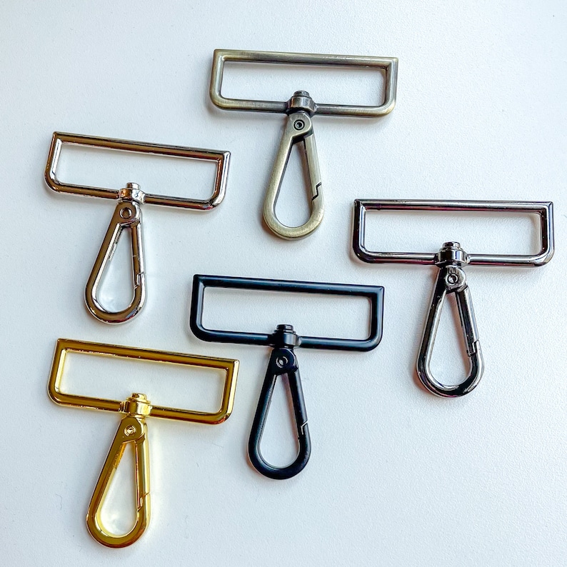 May include: Six different metal swivel clasps with rectangular loops and D-shaped rings. The clasps are in various finishes, including silver, gold, and black.