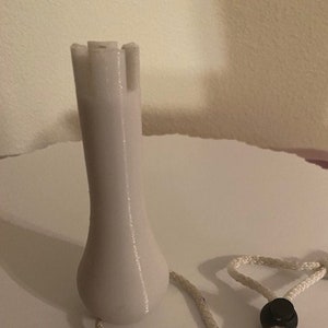 May include: A white plastic golf ball retriever with a rope handle. The retriever has a pointed end for retrieving golf balls from water hazards.