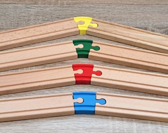 May include: Four wooden train track pieces with different colored puzzle pieces connecting them. The pieces are yellow, green, red, and blue.