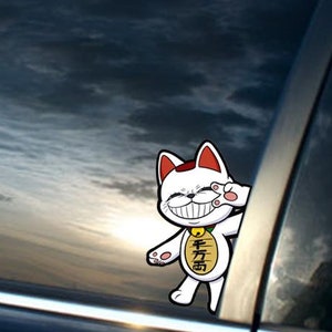 May include: A white cartoon cat with red ears and a gold coin with Japanese characters on its chest. The cat is smiling and waving with its right paw. The cat is on a car window with a cloudy sky reflected in the window.