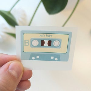 Könnte beinhalten: Ein blauer und gelber Kassettenband-Aufkleber mit dem aufgedruckten Text "mix tape".