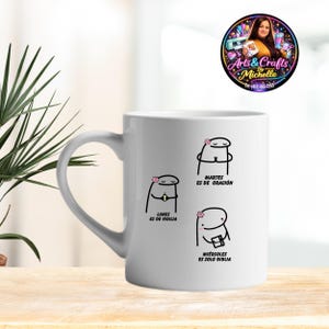 Może przedstawiać: Biały ceramiczny kubek z trzema postaciami z kreskówek, każda z kwiatowymi akcentami i hiszpańskim tekstem: "Lunes es de vigilia", "Martes es de oración" i "Miércoles es solo biblia". Kubek ma zakrzywiony uchwyt i logo.