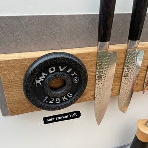 Peut inclure: Un porte-couteaux magn&eacute;tique en bois avec trois couteaux argent&eacute;s et une plaque de poids noire avec le texte "MOLIT 1.25 KG" et le texte "sehr starker Halt".