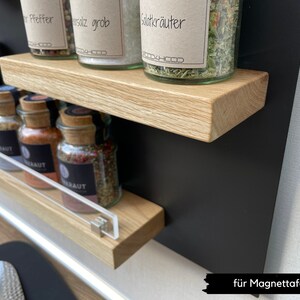 Puede incluir: Un conjunto de dos estantes de madera con una pizarra magn&eacute;tica negra detr&aacute;s. Los estantes est&aacute;n llenos de frascos de vidrio con especias, incluyendo sal, pimienta y hierbas. Los frascos tienen etiquetas con los nombres de las especias en alem&aacute;n. El texto en la pizarra magn&eacute;tica dice "f&uuml;r Magnettafeln".