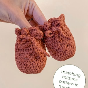 May include: A pair of crocheted baby booties in a terracotta color with a bow detail. Matching mittens pattern available in shop.